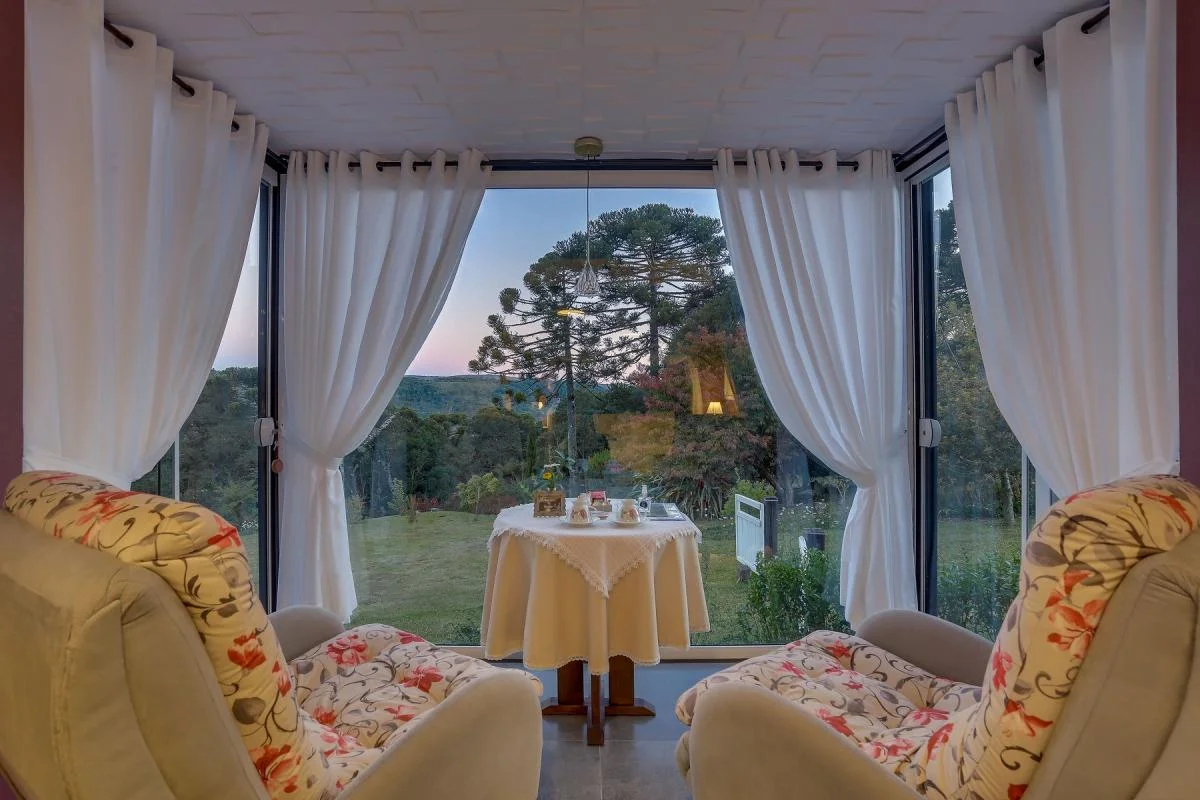 Espaço café com mesa posta e vista para o jardim.