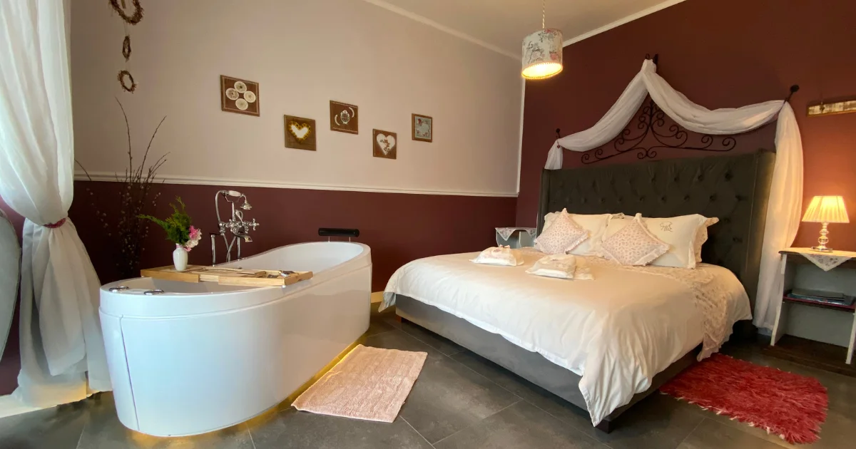 Suíte com decoração romântica e iluminação quente.