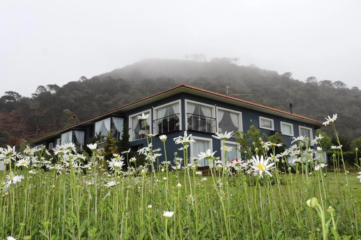 Construção principal da Pousada Cantos e Encantos integrada ao jardim.