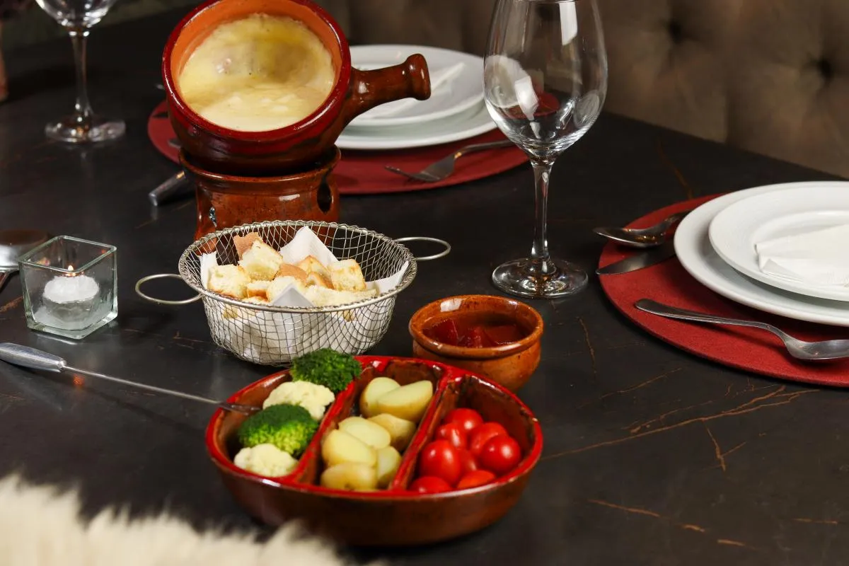 Mesa posta com fondue servido na Pousada Cantos e Encantos, experiência gastronômica intimista.