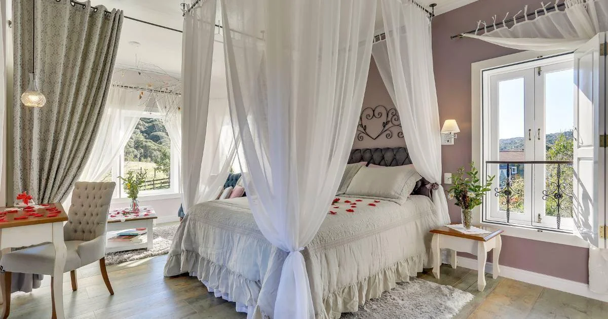 Cortinas leves e iluminação natural em suíte da pousada.