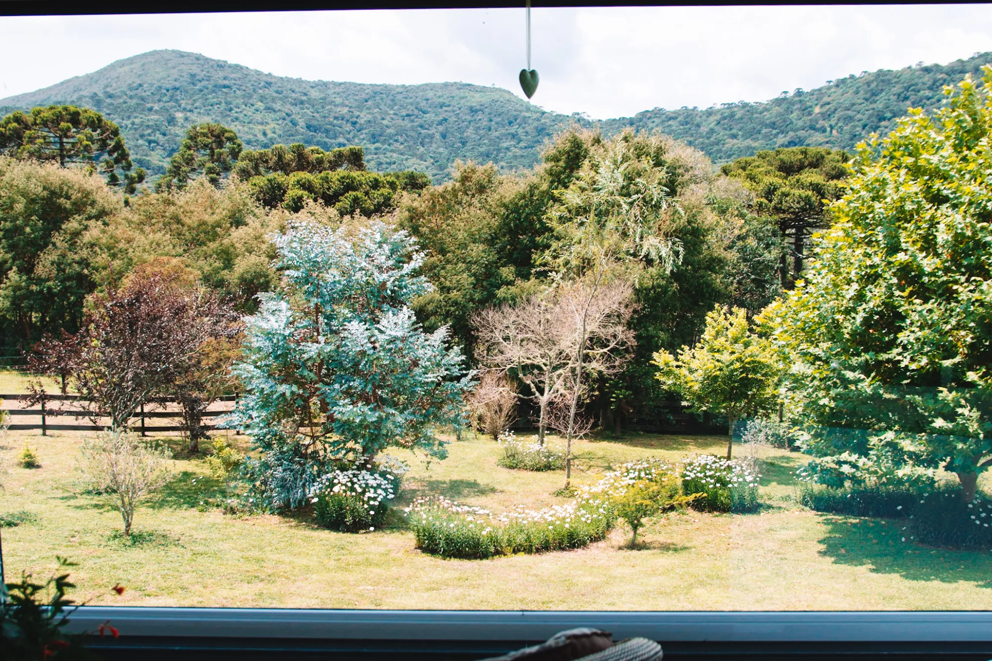 Vista para o jardim e para as montanhas a partir da Pousada Cantos e Encantos, em Urubici, com natureza preservada e clima ideal para descanso a dois.