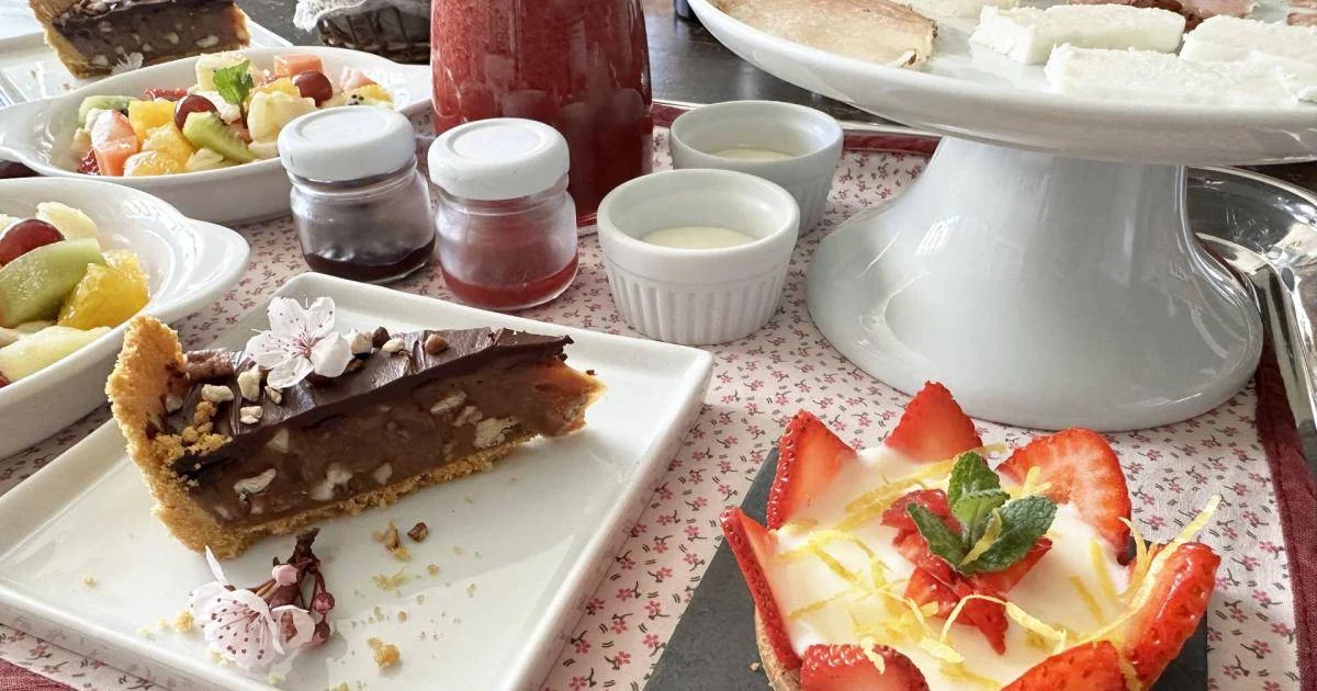 Mesa de café da manhã artesanal da Pousada Cantos e Encantos, com tortas caseiras, frutas frescas, geleias artesanais e sobremesas servidas em ambiente acolhedor em Urubici, na Serra Catarinense.