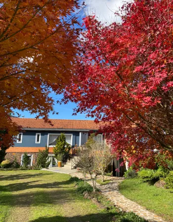 Jardim da Pousada Cantos e Encantos em Urubici durante o outono, com árvores de folhas avermelhadas
