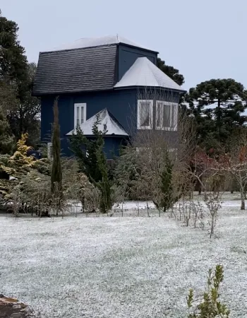 Vista do sobrado da Pousada Cantos e Encantos em Urubici cercado por vegetação em dia frio